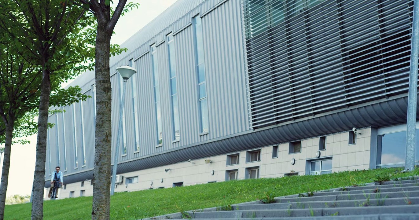 view from below of young man riding a bike close to a huge building