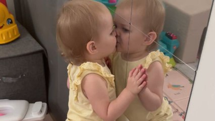 Adorable one-and-a-half-year-old girl greets her reflection in the mirror with aggressive kisses!