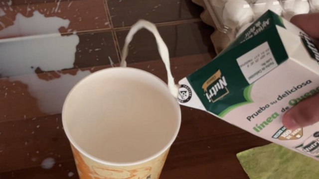 Boy tries to pour milk but milk misses glass and spills on the side