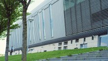 View from below of young man riding a bike close to a huge building