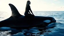 Jessica Radcliffe sitting on the back of an orca in the ocean