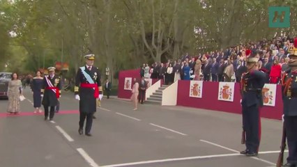 El rey pasa revista a la Guardia Real mientras de fondo hablan la reina Letizia y Pedro Sánchez