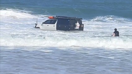 Hilux rolling into the surf creates an unreal scene at beach as two men chase after it
