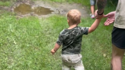 Little boy draws near puddle but slips and falls into it