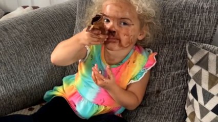 Little girl munches on ice cream and covers her whole face with it