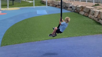 Young boy tries zip line ride on his own but takes a sudden tumble at the end of the track