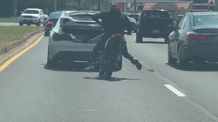 Footage of dirt bike rider falling off after suddenly losing control while doing a bizarre stunt with a car