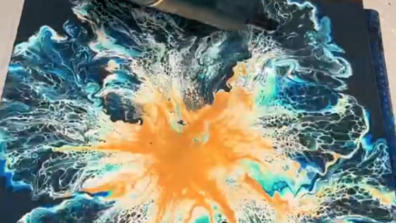 Artist creates a fluid art painting with acrylic pouring techniques