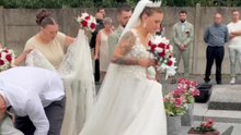 Girl lays a bouquet on her father's grave on her wedding day