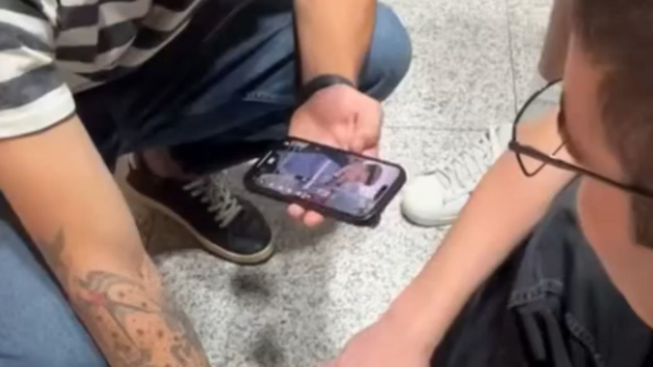 Boy twitches another boy's biceps and gives him a muscle cramp at the airport