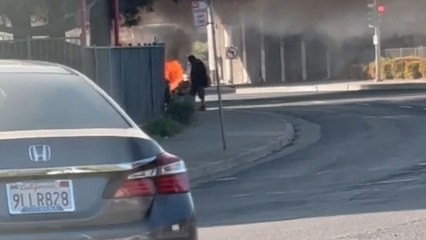 Burning vehicle captured on Broadway under Highway 99 as bystanders watch the blaze