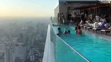 When luxury meets gravity_On a skyscraper rooftop_ the glass pool barrier shattered_ sending tons of water cascading down the tower._Swimmers froze in disbe(