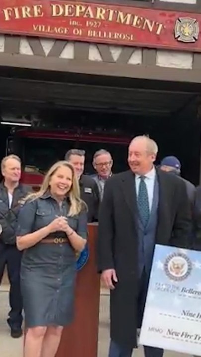 Laura Gillen raises a big check worth $938,000 in front of Bellerose Village Fire Department