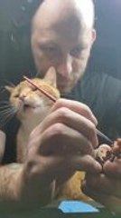 Cat Playfully Bites Brush as Man Tries to Paint