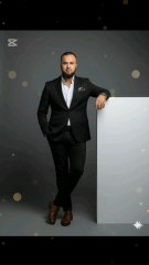 "Boss mode activated 🔥! Stylin' in a sleek black suit 💼, crisp white shirt 👕, and killer brown boots 🥇. Pocket square adds a pop of flair 😎. Leaning cool against a blank canvas 🖼️. #SuitsAndStyle #BusinessChic #PosingLikeABoss"