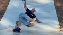 Man collides with his daughter at the end of a pumpkin patch slide