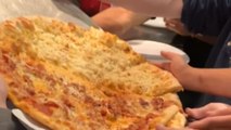 Woman watches her Hell's Kitchen pizza fall as the pan suddenly tips off the stand