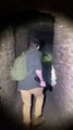 A man holding a flashlight discovers the entrance of a dark underground cave and slowly walks inside.