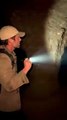 A man holding a flashlight discovers the entrance of a dark underground cave and slowly walks inside.2