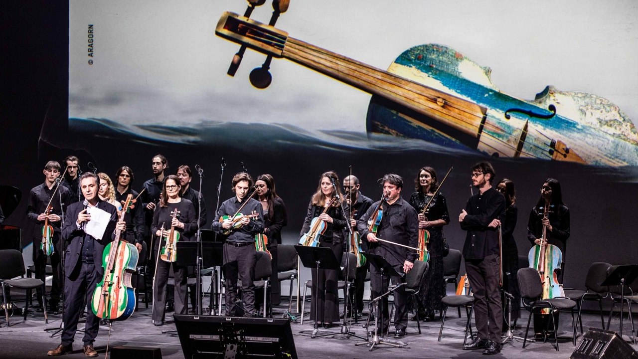 Piovani , Boni e l'Orchestra del Mare insieme sul palco, gli strumenti musicali costruiti con il legno delle barche dei migranti