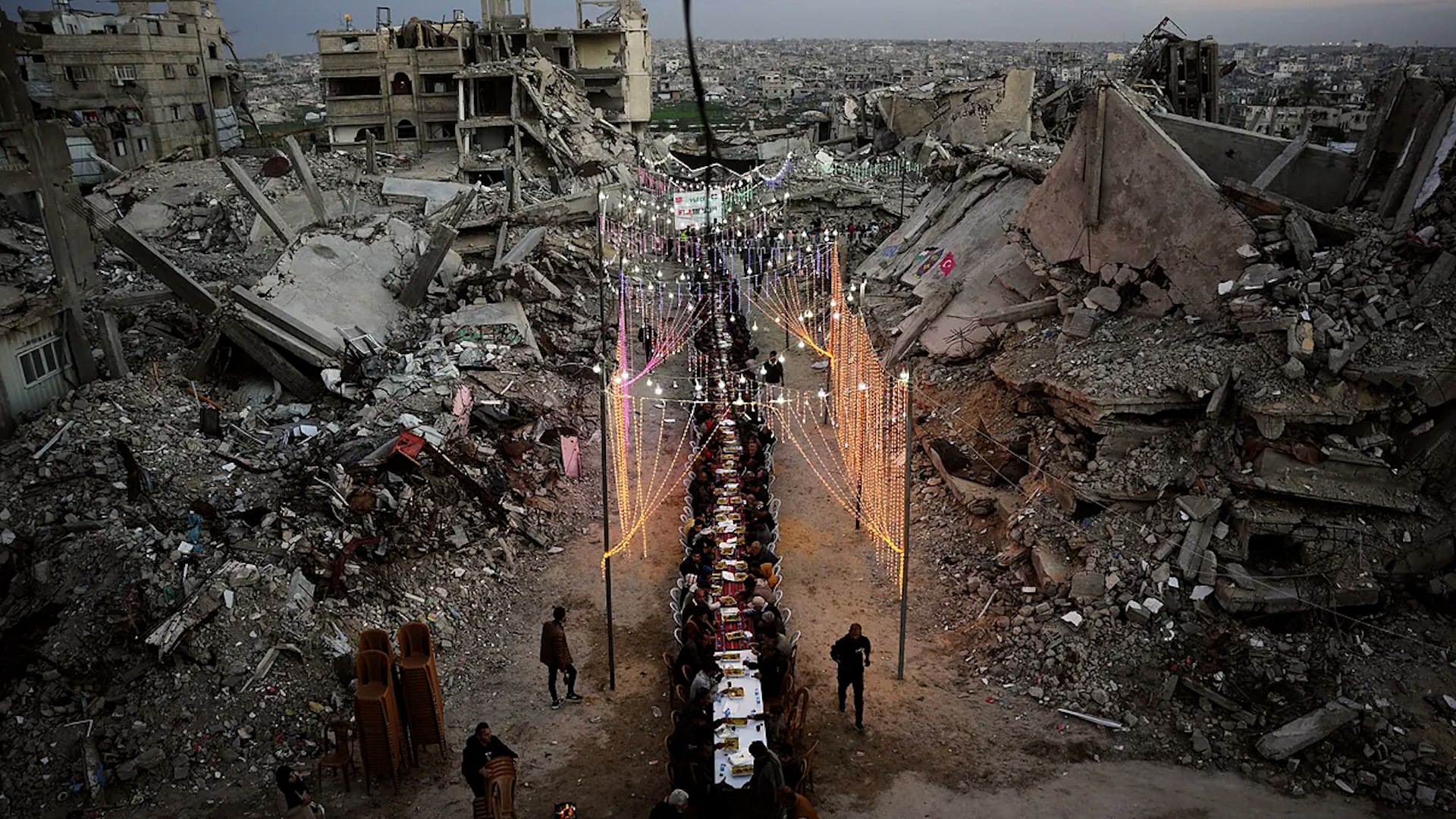 La poblaci�n de la Franja de Gaza afronta su tercer Ramad�n bajo el estruendo de la guerra, aunque este a�o el mes sagrado coincide con una tregua tan fr�gil como necesaria. A pesar del cese parcial de las hostilidades, la realidad sobre el terreno sigue marcada por la destrucci�n masiva, el hacinamiento y un bloqueo que impide la llegada de suministros vitales.
En Jan Yunis, la ciudad m�s grande del sur del enclave, familias como la de Reema intentan mantener vivas las tradiciones a pesar del dolor de las ausencias. Reema, una profesora que perdi� su hogar y a uno de sus tres hijos en un bombardeo, vive ahora en una tienda de campa�a tras ser desplazada en tres ocasiones. Para ella, el significado de estas fechas es agridulce: "Es dif�cil celebrar algo con todo lo que hemos perdido".
Junto a sus vecinos, ha improvisado mesas con tablas para romper el ayuno de forma comunitaria, una necesidad impuesta por la falta de recursos individuales. "Antes era un festivo que movilizaba a todo el barrio, ahora lo celebramos sobre todo por los ni�os, porque hay que seguir adelante", relata la docente. La log�stica del d�a a d�a se ha vuelto una lucha colectiva: "Antes cada vecino tra�a algo de casa pero ahora cocinamos juntos porque no tenemos hogar. Hacemos lo que podemos. Ahora hay m�s comida en el mercado, pero es muy cara".
Desde una perspectiva m�dica y humanitaria, la tregua ofrece un alivio estad�stico pero no una soluci�n real a la crisis. David Noguera, m�dico de M�dicos Sin Fronteras (MSF), advierte de que la calma es enga�osa: "Es una situaci�n que no es nada normal. Claro que se han logrado ciertos avances durante el alto el fuego, la ca�da de los �ndices de desnutrici�n lo indican. No avanzar hacia el exterminio total es bueno, pero el territorio est� como en pausa, no hay mejoras". Para muchos gazat�es, este periodo solo sirve para asimilar el trauma acumulado: "La tregua ha impactado mucho a la poblaci�n porque todo este tiempo han estado corriendo, huyendo. Ahora es cuando tienen un momento de pausa para pensar, para crear cierta estabilidad en sus vidas".
La geograf�a del conflicto tambi�n ha cambiado; los palestinos se encuentran ahora hacinados en el 53% del territorio, mientras Israel controla el 47% restante tras una "l�nea amarilla" donde se siguen produciendo incidentes. Michail Fotiadis, coordinador de emergencias de MSF, define la situaci�n actual de forma tajante: "Es un alto el fuego con actividades militares". A pesar del silencio relativo de las armas, 600 palestinos han muerto en ataques israel�es desde que comenz� la tregua.
La habitabilidad en la Franja es pr�cticamente inexistente, con un 83% de los edificios destruidos. Las condiciones sanitarias son cr�ticas, con familias viviendo bajo pl�sticos y maderas que se inundan con las lluvias. Seg�n Noguera, "todos los sistemas est�n por iniciar", refiri�ndose a la salud, educaci�n y urbanismo.
Adem�s, las organizaciones humanitarias denuncian un bloqueo sistem�tico de materiales esenciales. Israel proh�be la entrada de sillas de ruedas y productos con glicerina por motivos de seguridad. "Todas las cremas que llevan glicerina est� prohibido porque (Israel) cree que se puede destilar para hacer bombas. Tampoco nos dejan entrar sillas de ruedas. Este tipo de cosas sinsentido", denuncia Noguera. Esta escasez ha fomentado un mercado negro donde los materiales prohibidos alcanzan precios astron�micos: "Nosotros tambi�n tenemos m�s materiales, pero seguimos con limitaciones masivas. No nos dejan entrar (a Gaza) ciertas medicinas, materiales de construcci�n y el�ctrico para hospitales. Es curioso porque han aparecido muchas de estas cosas en el sector privado, en el mercado negro, porque como siempre en las guerras hay gente que se hace rica".
La situaci�n tiende a agravarse debido a las nuevas leyes de registro impuestas por Israel, que afectan a 37 ONGs, incluida MSF. Desde enero, el ingreso de medicamentos y personal especializado est� bloqueado. Fotiadis alerta sobre el agotamiento de los recursos: "Como otras organizaciones humanitarias, durante toda la guerra hemos tenido problemas para trabajar en Gaza, pero desde enero no podemos traer m�s medicamentos". La presi�n sobre el personal local es insostenible: "Tampoco staff especializado. Los que se encontraban en Gaza han tenido que doblar rotaci�n. Ahora estamos utilizando lo que tenemos, pero alg�n d�a no vamos a tener m�s".
El Ramad�n transcurre as� entre la esperanza de que la comida llegue a los mercados y el temor constante de que los suministros m�dicos se agoten definitivamente. Mientras tanto, la poblaci�n sigue viviendo en una precariedad extrema donde "tiendas de campa�a" es solo un eufemismo para designar refugios de pl�stico entre escombros.