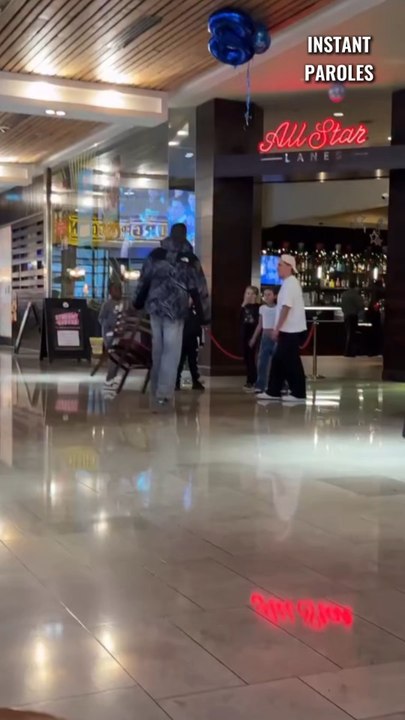 Ce passant aide ces enfants à récupérer leurs ballons gonflables dans ce centre commercial