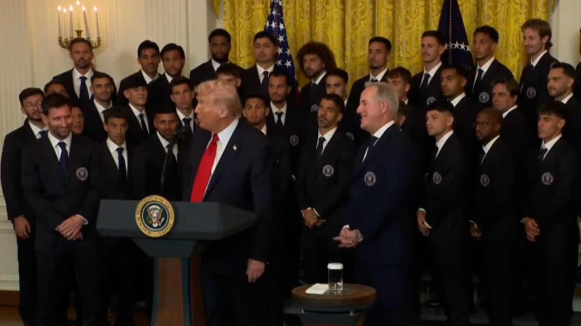 El Sal�n Este de la Casa Blanca fue testigo este jueves de un encuentro hist�rico para el deporte estadounidense. El presidente Donald Trump recibi� al Inter Miami, vigentes campeones de la MLS, encabezado por su gran estrella, Lionel Messi. En un acto cargado de simbolismo, el mandatario estadounidense no escatim� en elogios hacia el astro argentino, llegando a situarlo por encima de leyendas hist�ricas del f�tbol mundial.
Uno de los momentos m�s comentados de la recepci�n fue cuando Trump, recordando su juventud, compar� a Messi con el astro brasile�o Pel�, a quien vio jugar en su etapa con el Cosmos de Nueva York. El mandatario se rindi� ante la calidad del rosarino con unas palabras que ya han dado la vuelta al mundo: "No deber�a decir esto porque luego dir�n que estoy viejo, pero yo vi jugar a Pel�. Jugaba en el Cosmos. No lo s�&mldr; Puede que t� seas mejor que Pel�. Pel� era bastante bueno. �Qui�n es mejor? �T�? Yo creo que s�&mldr; Pero �l era muy bueno, �verdad? Pel� era muy bueno".
Para Trump, el m�rito de Messi en Estados Unidos no reside solo en su talento, sino en su capacidad para cumplir con las alt�simas expectativas generadas desde su llegada en 2023. El presidente destac� que, a diferencia de otras estrellas internacionales que llegaron a la liga sin lograr el �xito, Messi transform� al Inter Miami en un equipo ganador de inmediato.
Dirigi�ndose directamente al capit�n argentino, Trump afirm�: "T�, Leo, llegaste y ganaste, y eso es algo muy dif�cil, muy inusual. Adem�s, soportaste mucha m�s presi�n de la que nadie imagina, porque se esperaba que ganaras&mldr; y casi nadie lo logra. T� llegaste y ganaste con toda esa presi�n. Eso es un homenaje incre�ble". En la misma l�nea, el presidente recalc� la dificultad de su haza�a: "Leo, llegaste y ganaste, y eso es algo muy dif�cil de hacer, muy, muy inusual y, francamente, hay mucha m�s presi�n sobre ti de la que cualquiera se imaginar�a, porque se esperaba que ganaras, pero casi nadie gana".
El presidente del Inter Miami, Jorge Mas, tambi�n tom� la palabra para recordar el ambicioso plan que inici� en 2019 para llevar al equipo a la cima. "Me dije a m� mismo lo que muchos cre�an imposible. Dije: vamos a traer al mejor jugador del mundo para que juegue en el Inter Miami, y eso fue en 2019. Y hoy, frente a ustedes, tienen al mejor jugador del mundo". Mas subray� ante el presidente que el equipo que ten�a detr�s era, actualmente, "uno de los mejores equipos del planeta".
La ceremonia cont� con la presencia de figuras clave del vestuario como Luis Su�rez y los argentinos Tadeo Allende y Rodrigo De Paul. El Inter Miami, que se impuso a los Whitecaps de Vancouver en la final de diciembre, ha hecho historia al ser el primer equipo de la MLS invitado a la Casa Blanca durante los mandatos de Trump.
Este reconocimiento llega en un momento de gran expectaci�n por el Mundial 2026, que se celebrar� en Estados Unidos, Canad� y M�xico. A sus 38 a�os, se espera que Messi lidere de nuevo a la albiceleste en un torneo que, sin embargo, se ve condicionado por la inestabilidad internacional, incluyendo la guerra con Ir�n (selecci�n que tiene partidos programados en suelo estadounidense) y la agitaci�n en M�xico. Pese al contexto global, la figura de Messi, ganador de ocho Balones de Oro, sigue siendo el principal motor de ilusi�n para el f�tbol en Norteam�rica.