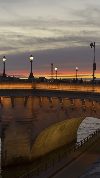 A static, breathtaking shot captures a Parisian bridge under a beautiful pink sky, leading the eye toward the distant, glowing Eiffel Tower.