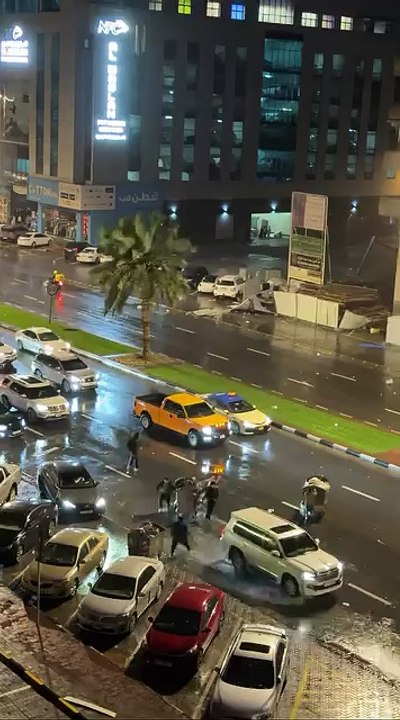 Residents removing large garbage bins blown into traffic