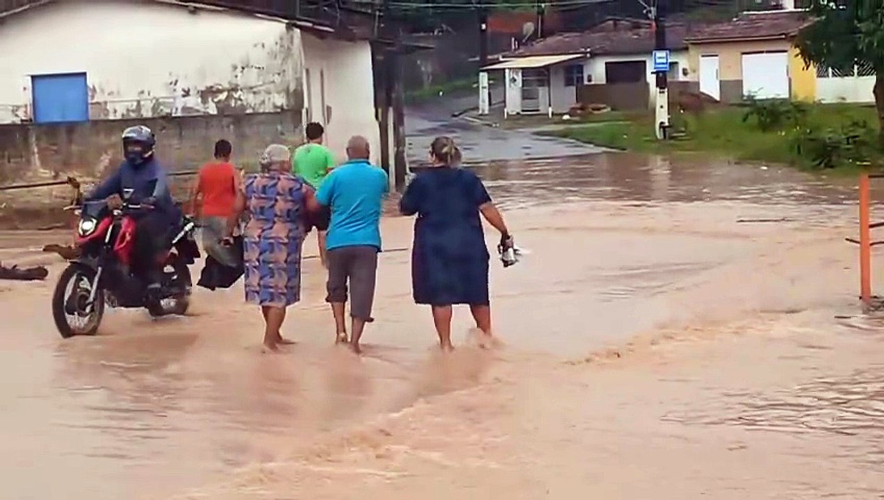Grupo de pessoas se arrisca andando em local inundado em Maceió