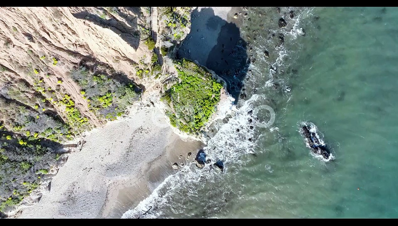 Aerial top view of ocean blue waves break on a beach.