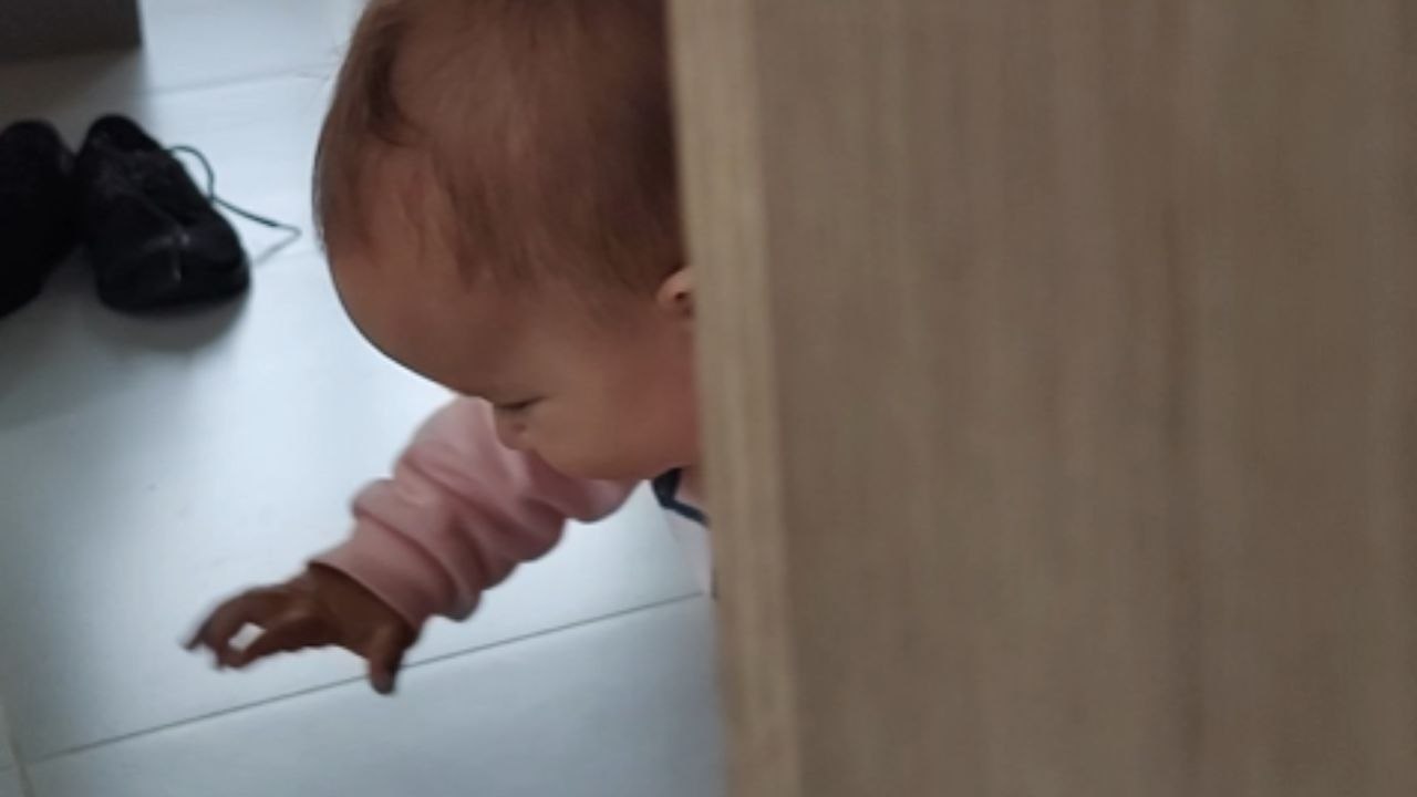 Adorable 8-month-old baby crawls after a bug on the floor, trying to catch it