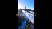 Aerial View of Snowy Ski Resort with Chairlift Forest and Sunlit Mountain Slope
