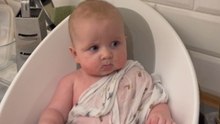 Little boy isn't too thrilled about bath time in the kitchen sink