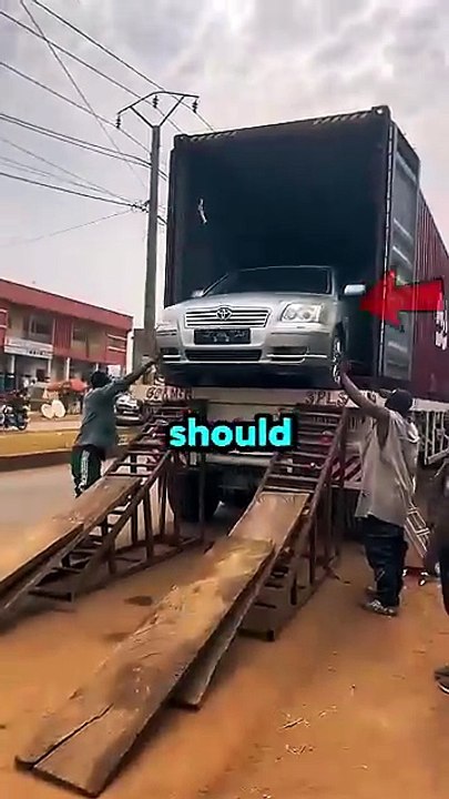 A brand new $100,000 car was being unloaded using sketchy metal ramps and wooden planks.