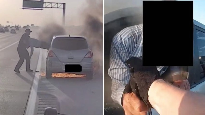 Cop drags motorist out of smoking car as it bursts into flames on side of the highway