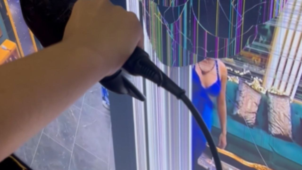 Woman Uses A Hairdryer To Reduce A Blotch On A Damaged TV Screen