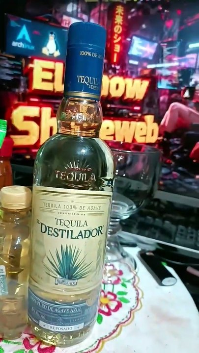 presentando una botella de tequila destilador y una bolsa de tostachos de la marca Barcel viernes