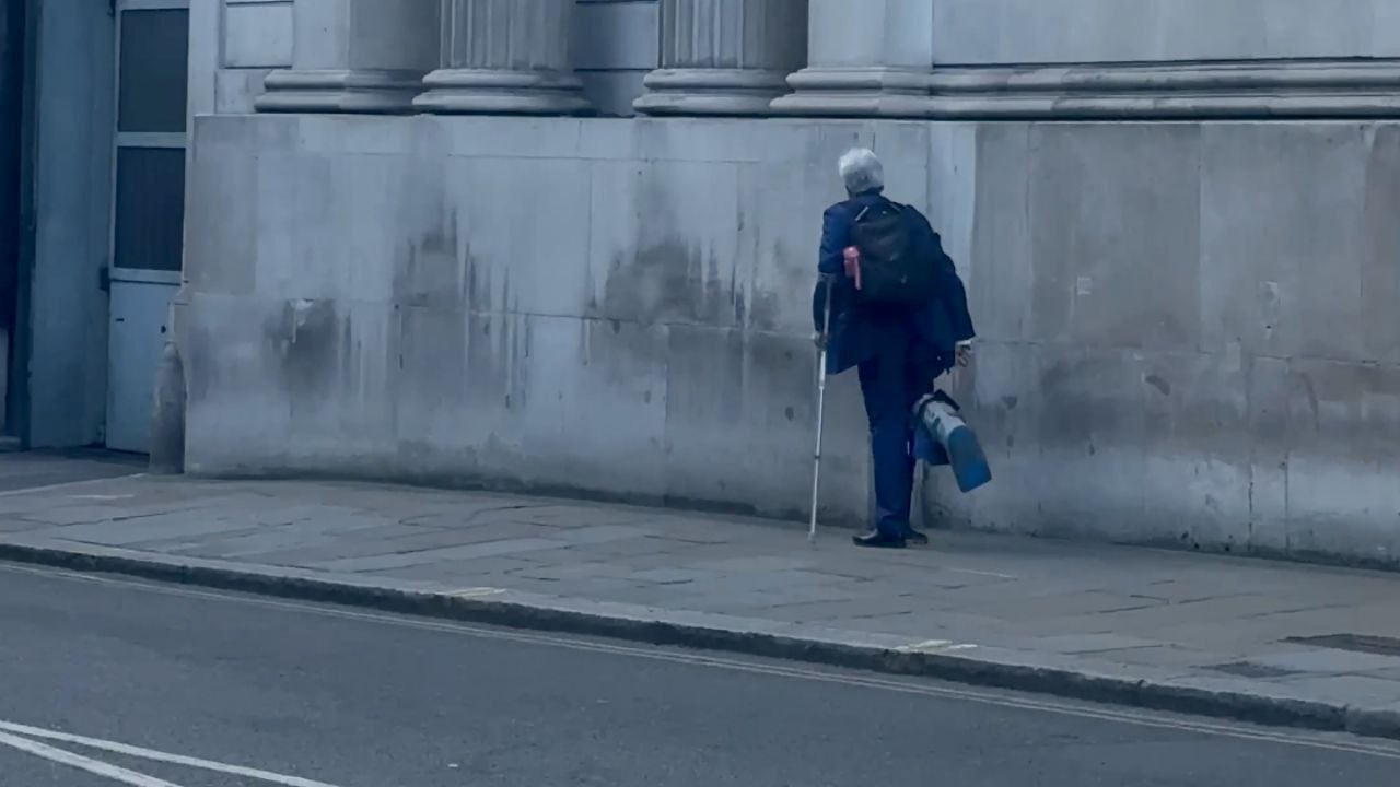 Suited Man With Crutches Moves Through Financial District