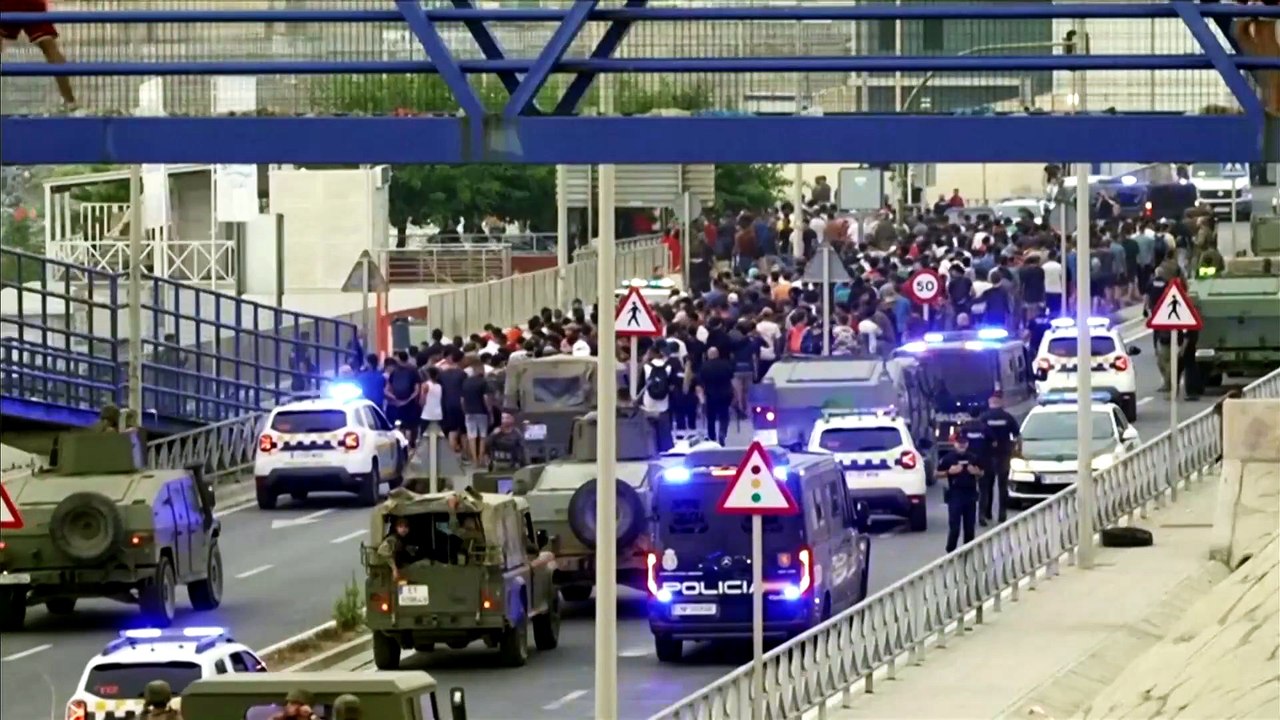 Military and police escort swarm of migrants out of Spain's Ceuta enclave