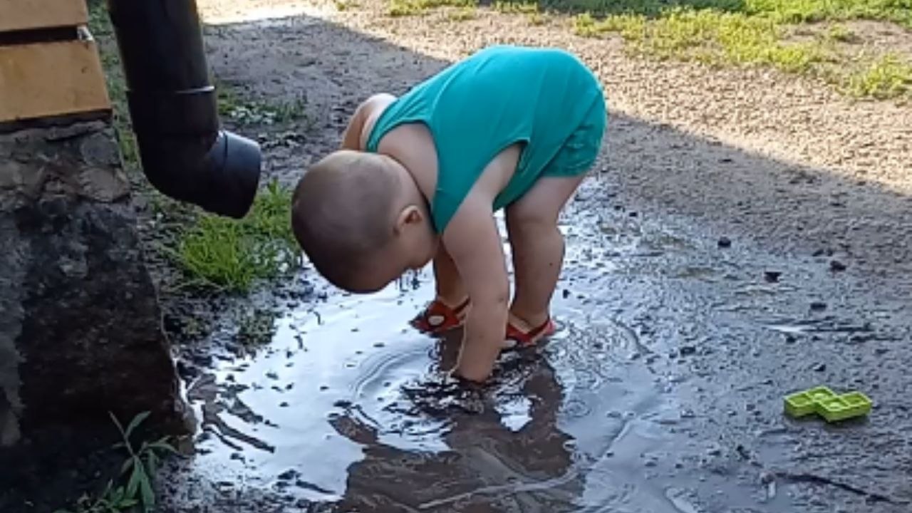 Young Boy Joyfully Dives Headfirst into Puddle
