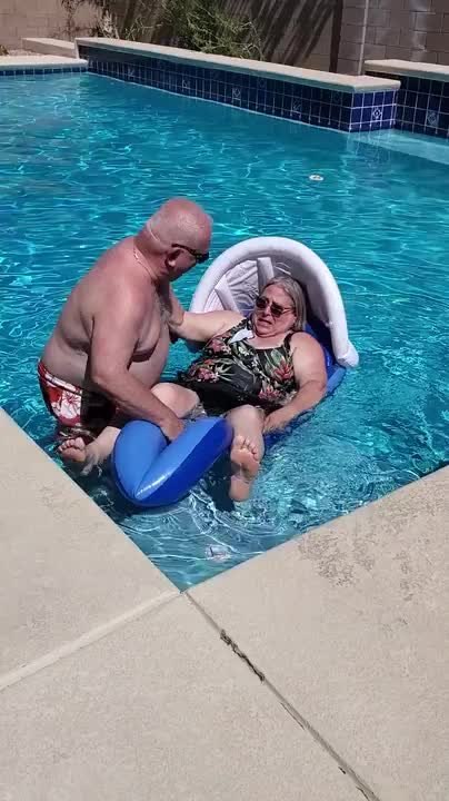 Elderly Man Helps Wife Get Onto Pool Float