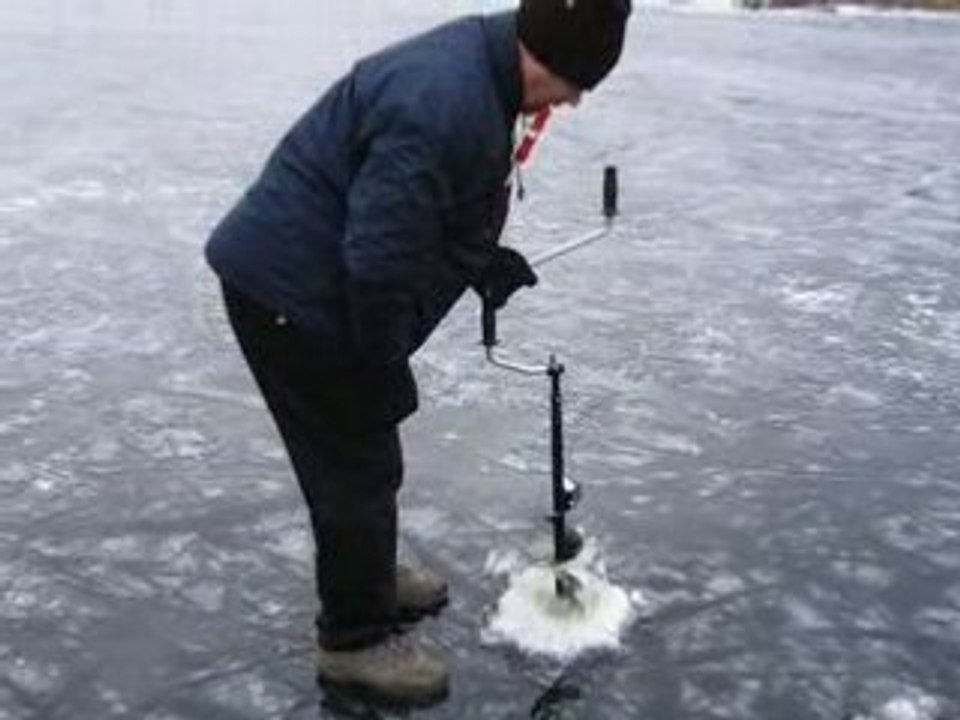 un pêcheur qui fait un trou dans la glace